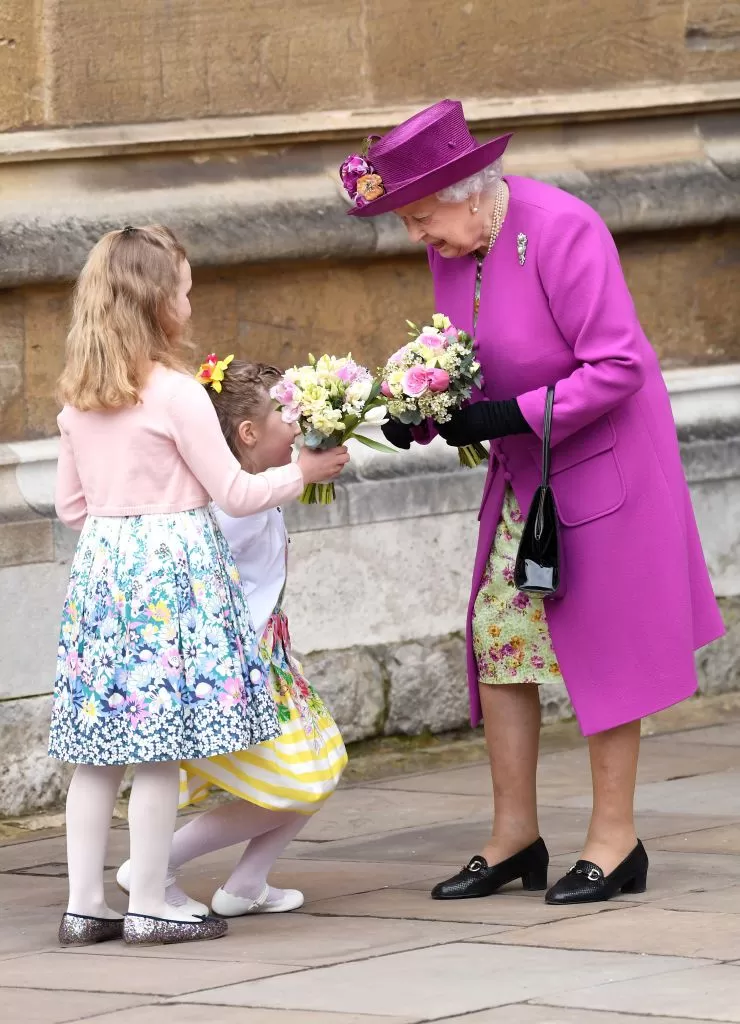 Королева Елизавета II принимает цветы от детей на Пасхальном богослужении.